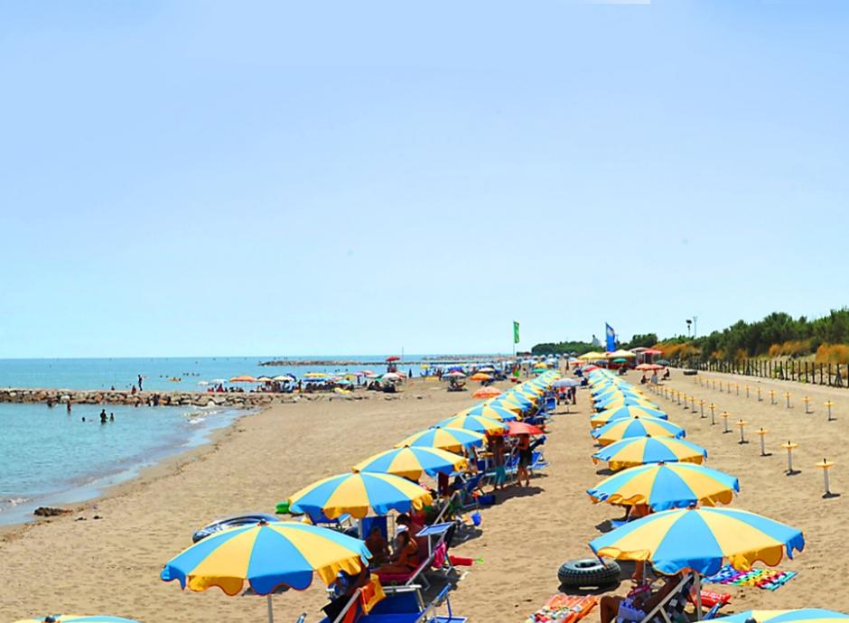 Spiaggia con ombrelloni colorati e lettini, gente che si rilassa al sole.