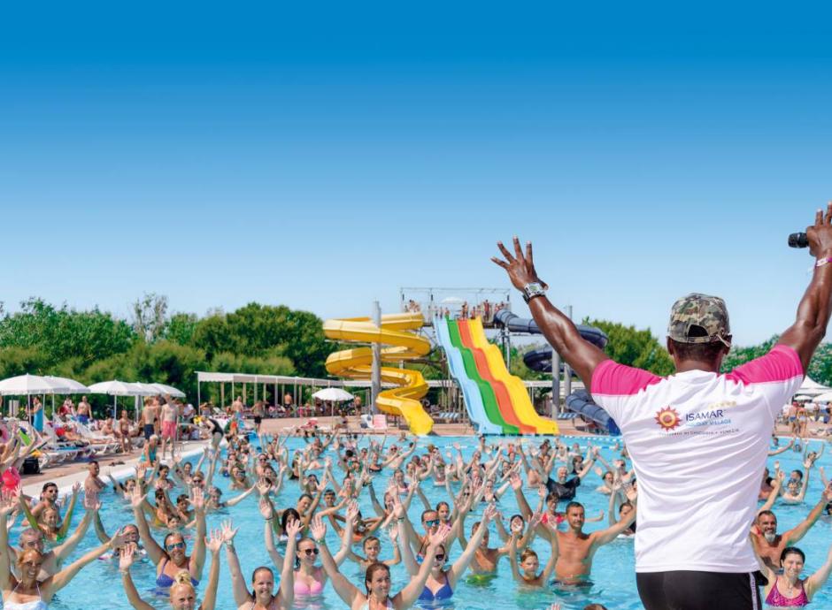 Persone che ballano in fila sulla spiaggia durante una festa estiva.